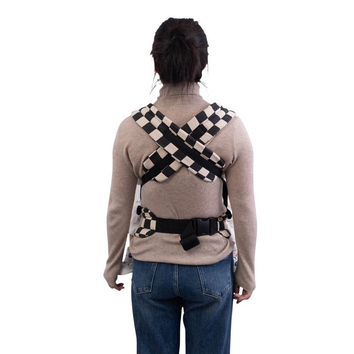 Person wearing a checkered baby carrier for newborn on a white background