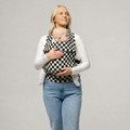 Woman holding a baby in a checkered baby carrier against a plain background